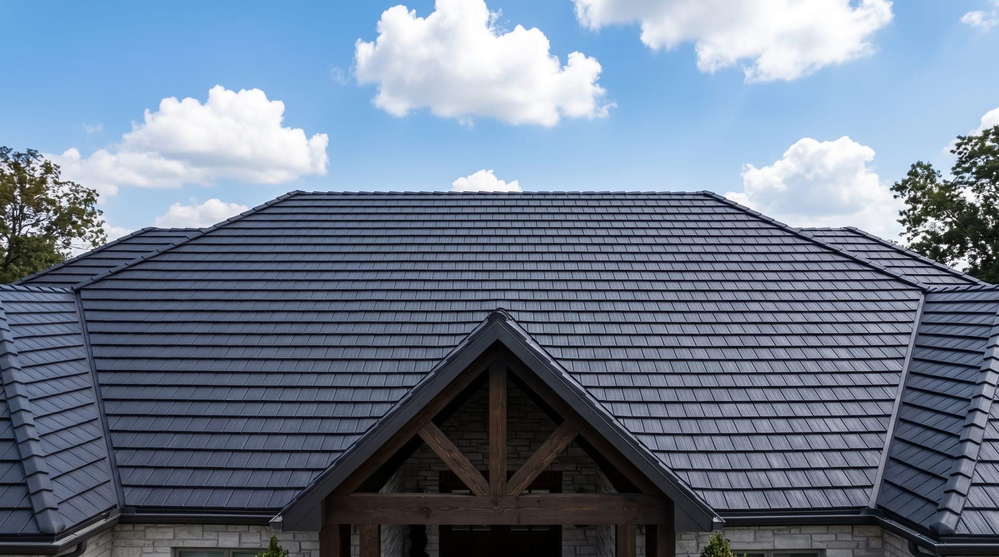 A finished dark shingle roof with a timber-framed entry gable under a blue sky
