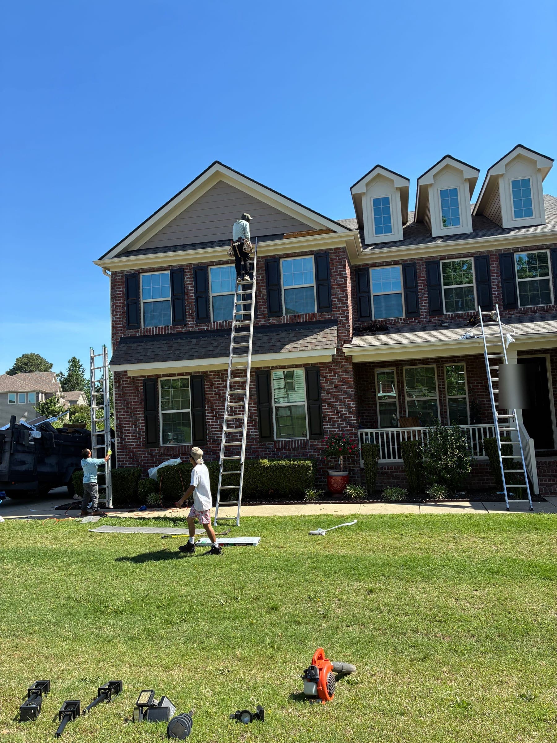 Megalo crew setting ladders and working on a brick two-story home